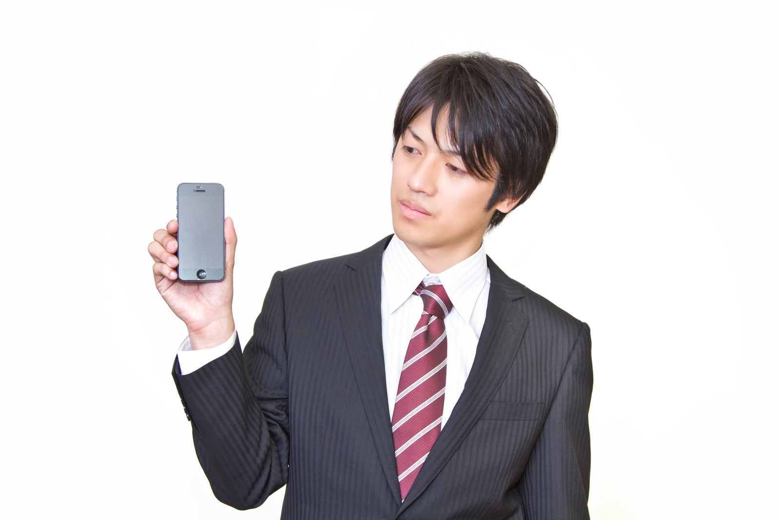 「世代前のスマートフォンを手に持つサラリーマン」の写真［モデル：Tsuyoshi.］