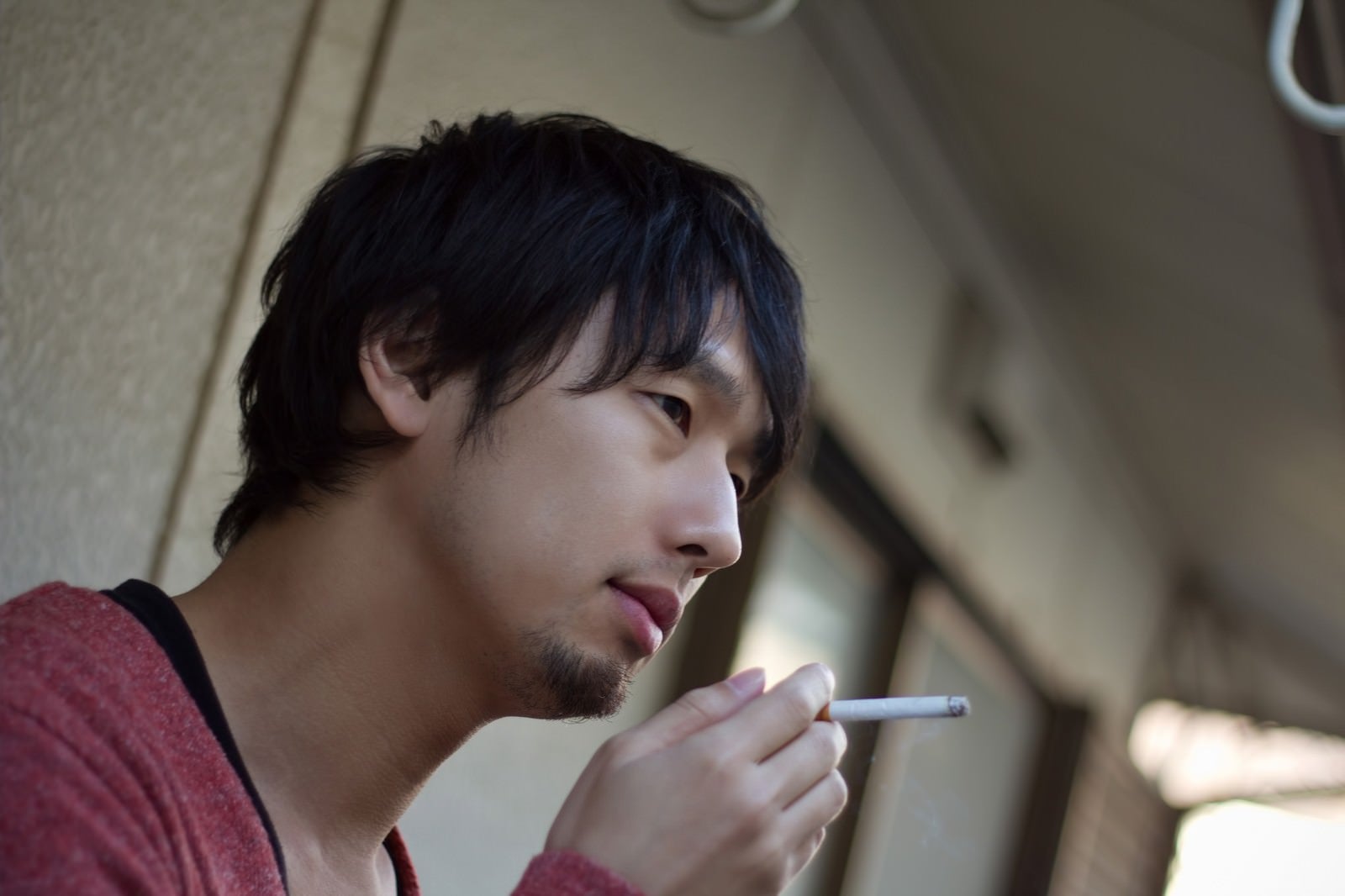 「ベランダで煙草を吸う男性」の写真［モデル：大川竜弥］