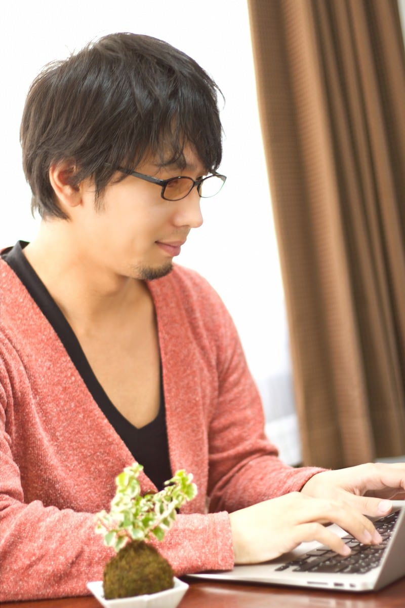 「PCを触る色眼鏡をかけた男性」の写真［モデル：大川竜弥］