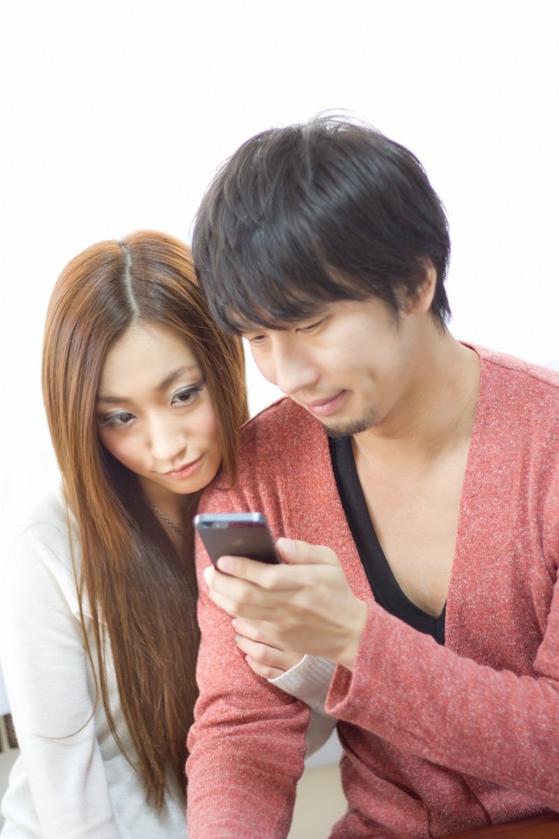 「スマホでアプリを楽しむ恋人」の写真［モデル：大川竜弥 北野佑々］