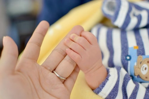 母の手を握る赤ちゃんの手の写真