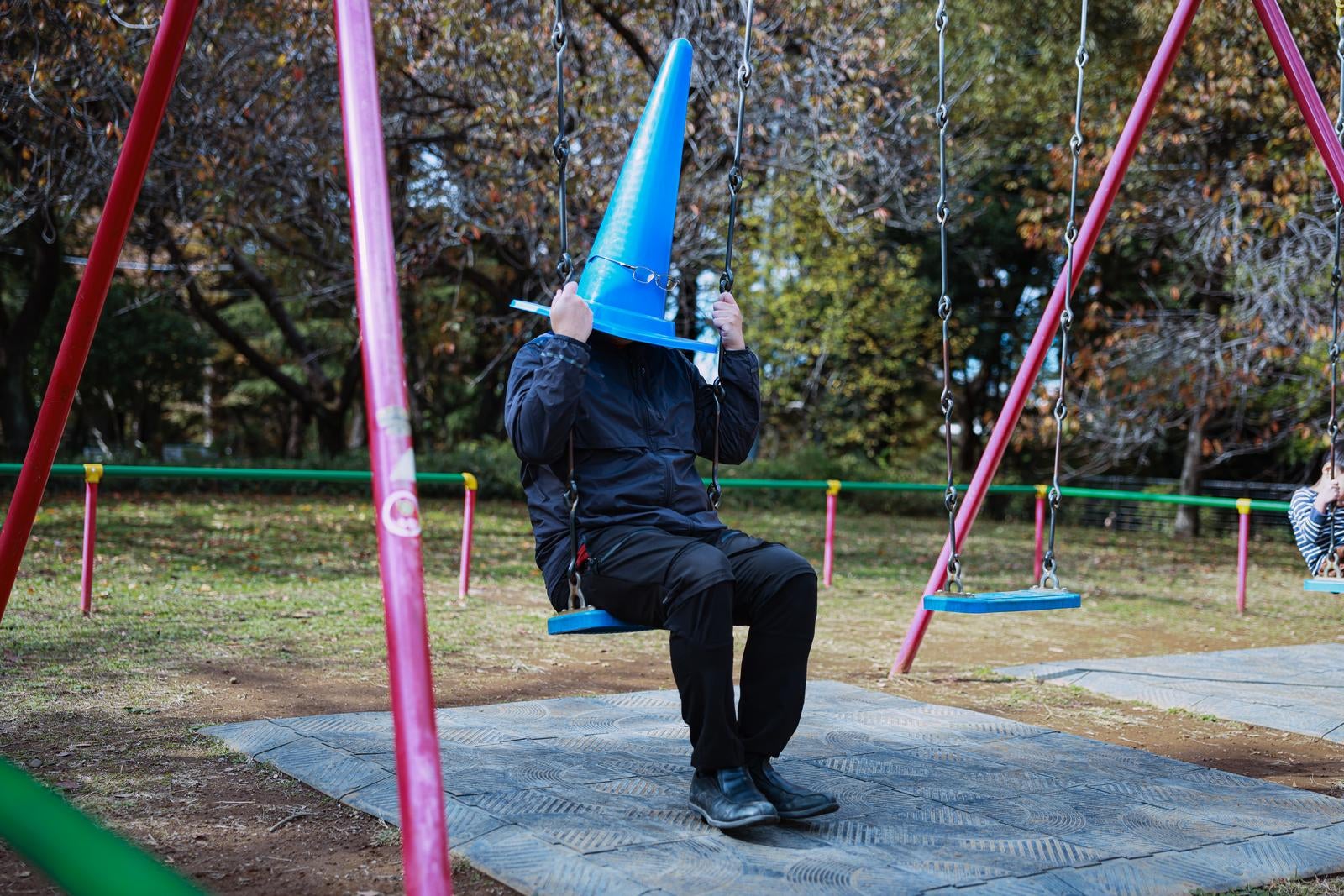 「失職して公園ブランコの三角コーンマン」の写真