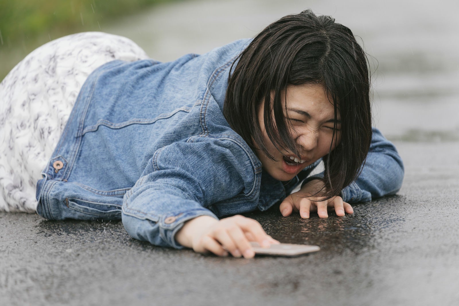 「歩きスマホで転倒し泣き叫ぶ女性（雨天）」の写真［モデル：佐竹PP］