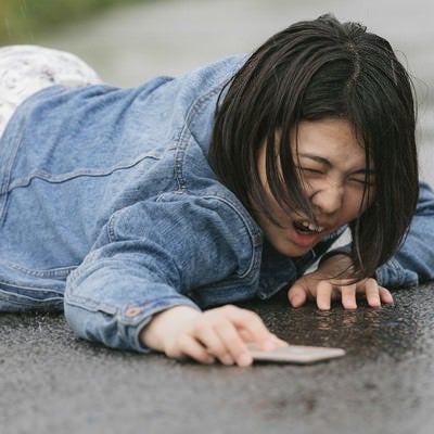 歩きスマホで転倒し泣き叫ぶ女性（雨天）の写真