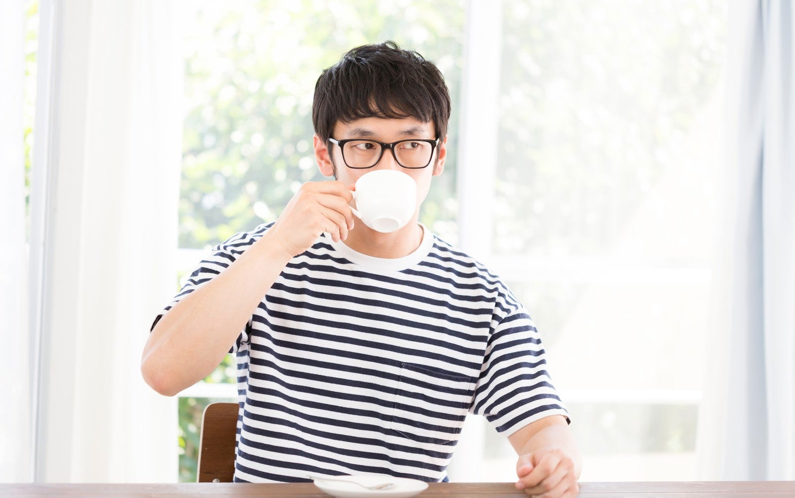 「リビングで深煎りコーヒーを飲む男性」の写真［モデル：大川竜弥］