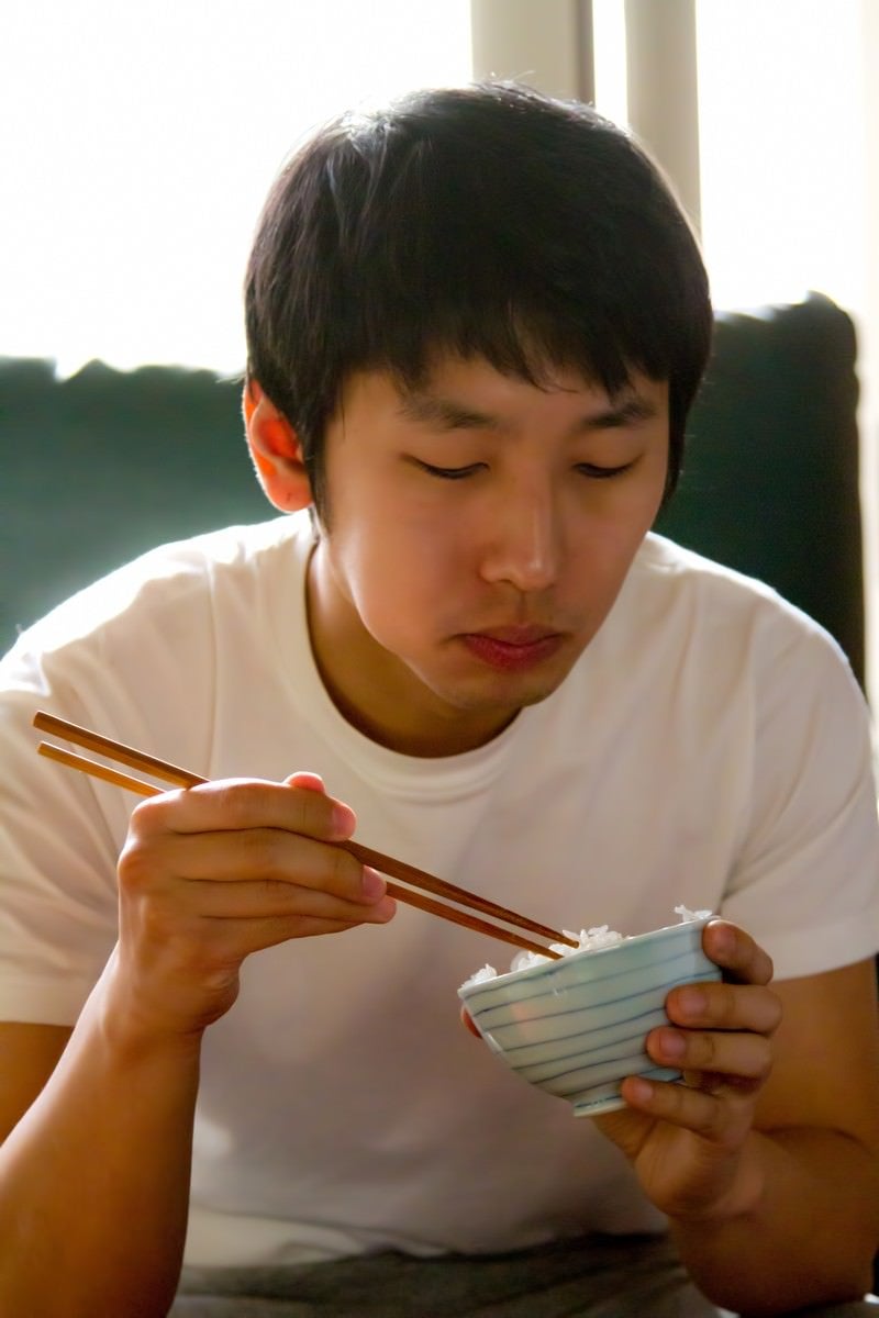 「ご飯をもぐもぐする男性」の写真［モデル：大川竜弥］
