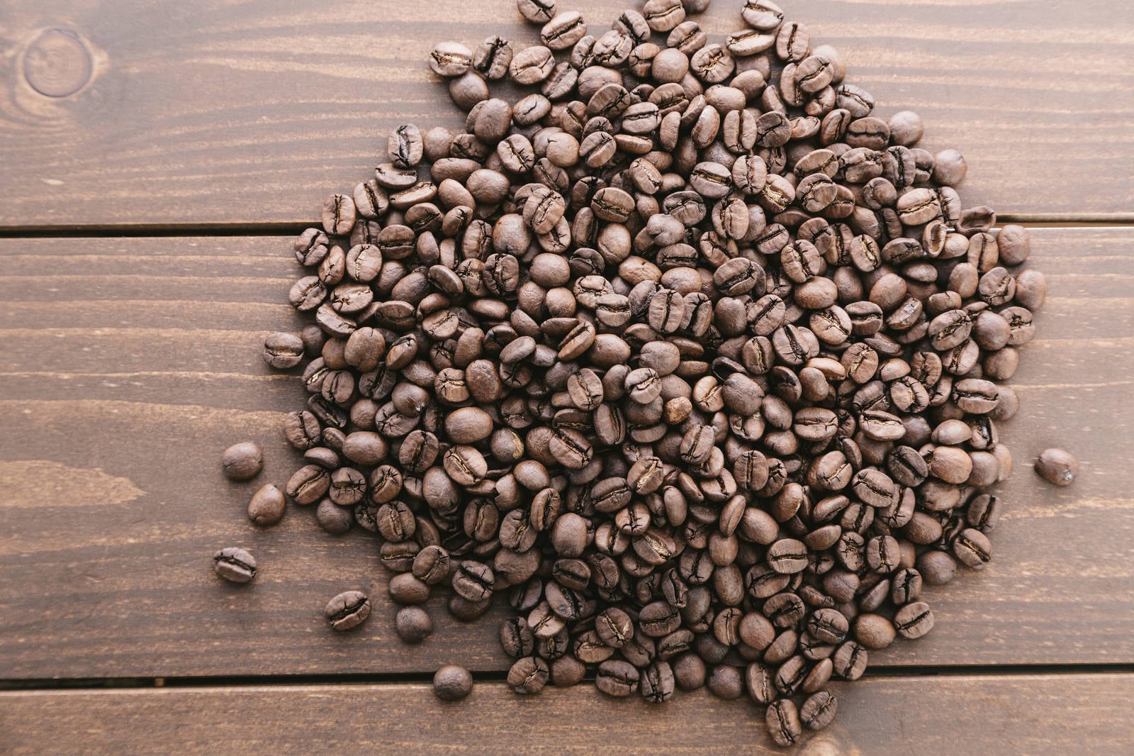 「木目のテーブルとコーヒー豆」の写真