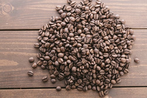木目のテーブルとコーヒー豆の写真