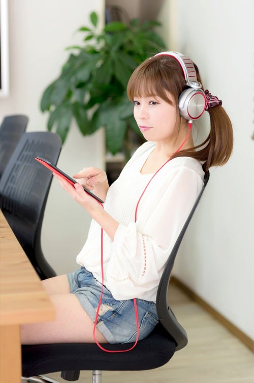 iPad mini で音楽を聴くホットパンツの女性の写真
