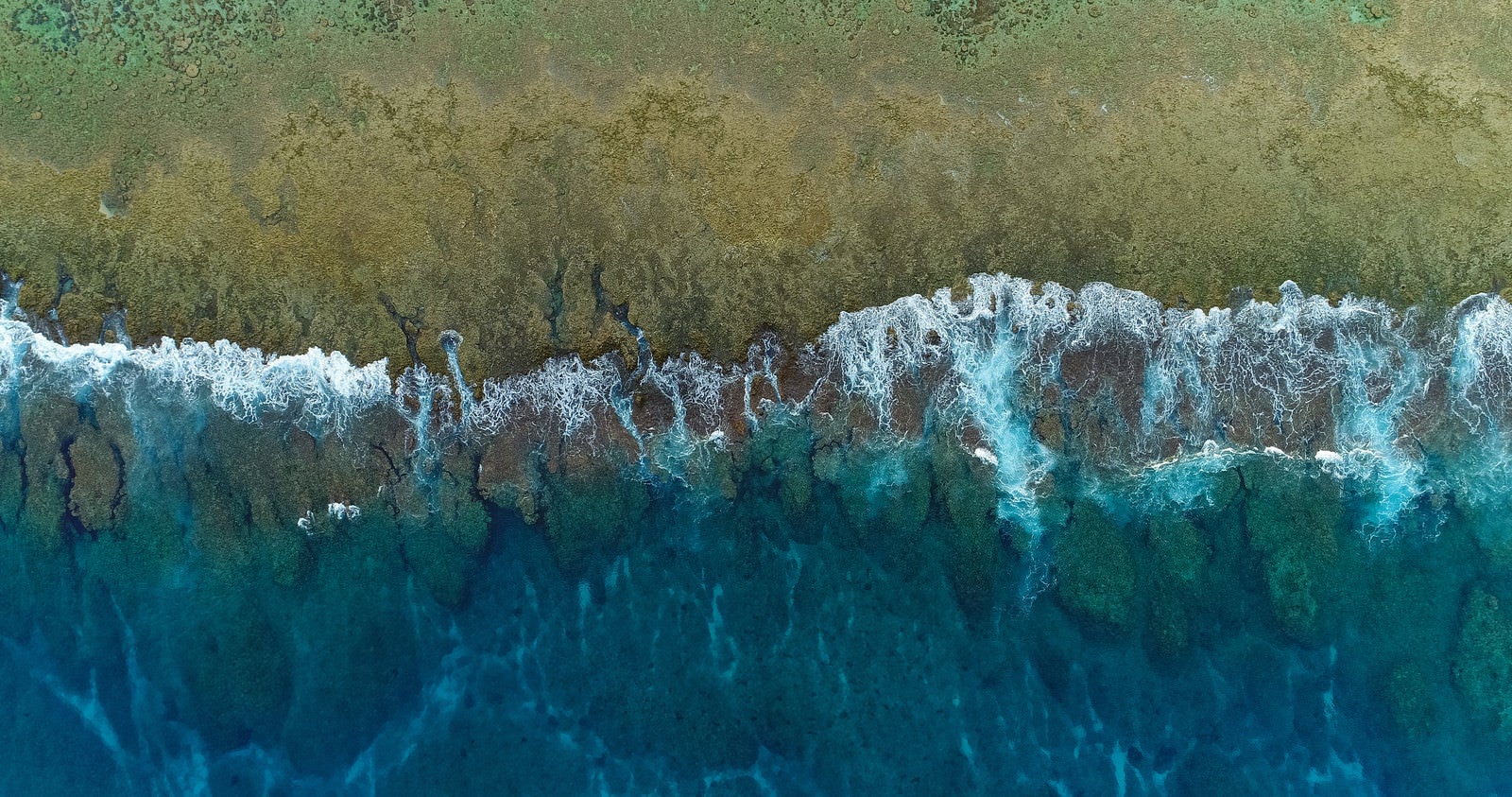 「徳之島の珊瑚礁に囲まれた透明感ある海と波（空撮）」の写真