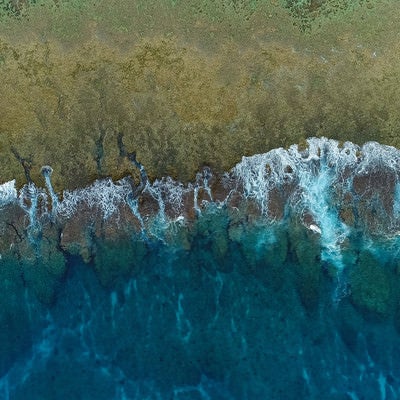 徳之島の珊瑚礁に囲まれた透明感ある海と波（空撮）の写真