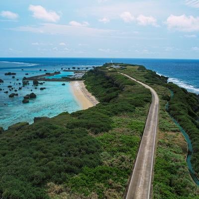 平安名埼灯台まで続く道と美しい岩礁の海（空撮）の写真
