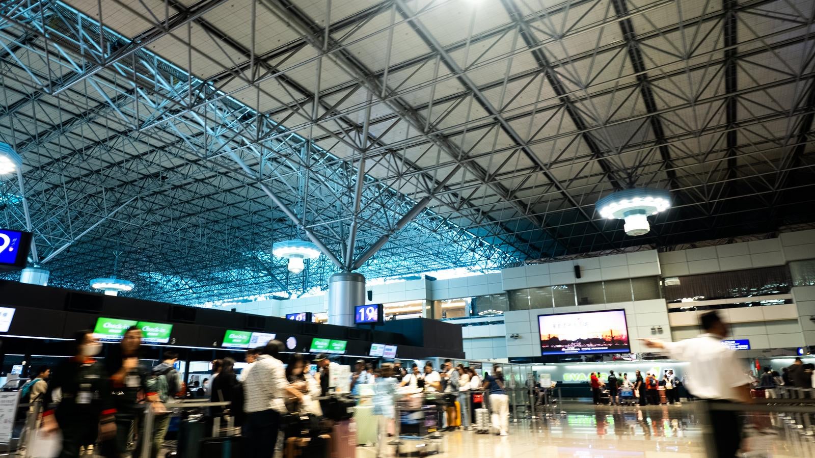 「チェックインカウンター前で手続きを待つ人々」の写真