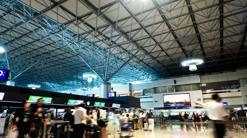 チェックインカウンター前で手続きを待つ人々の写真