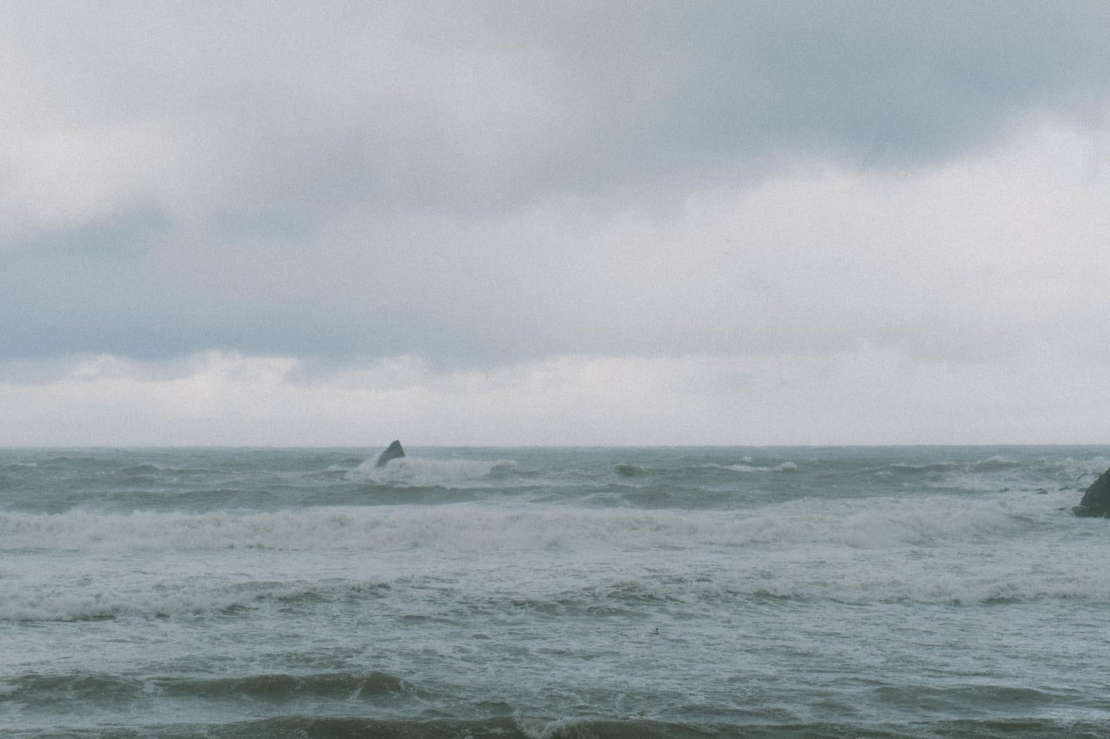 荒れる日本海で波に飲み込まれる岩 photo