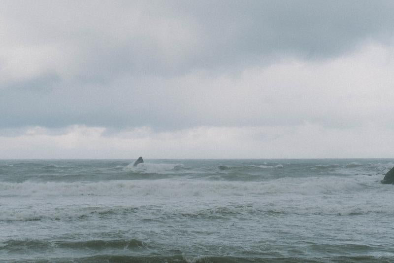 荒れる日本海で波に飲み込まれる岩の写真