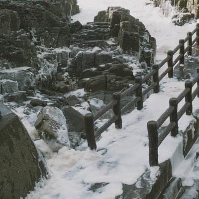 日本海の荒波と波の花が覆う遊歩道の写真