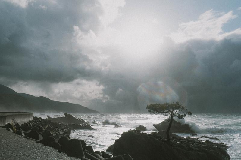 雲間からのぞく太陽に照らされて輝く日本海の写真