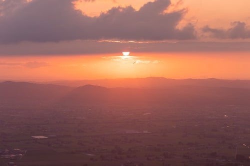 沈みゆく夕日と黄昏時の散居村（富山県南砺市）の写真