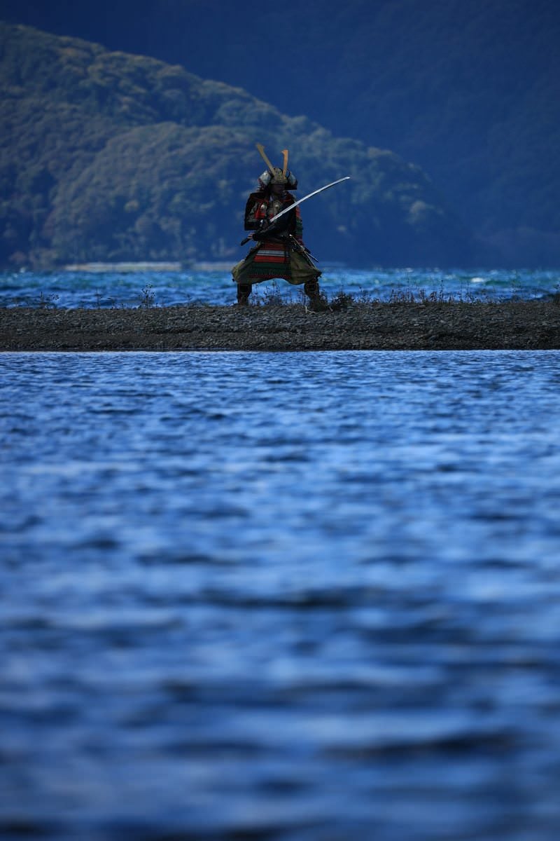 水辺の中州で太刀を構える甲冑姿の侍