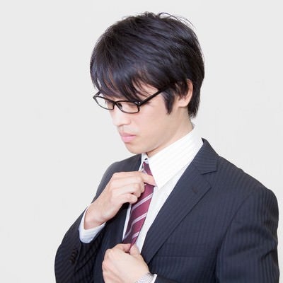 ネクタイを直す眼鏡をかけたサラリーマンの写真