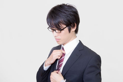 ネクタイを直す眼鏡をかけたサラリーマンの写真