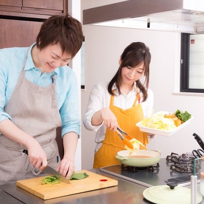 キッチンでお鍋を一緒に作っている夫婦の写真