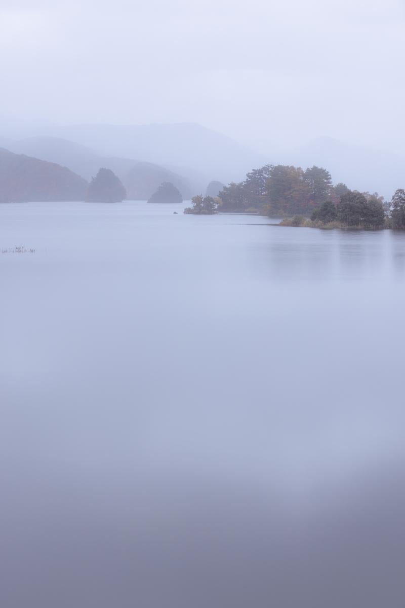 「朝霧が包む秋元湖と静けさの中の神秘的な朝」の写真