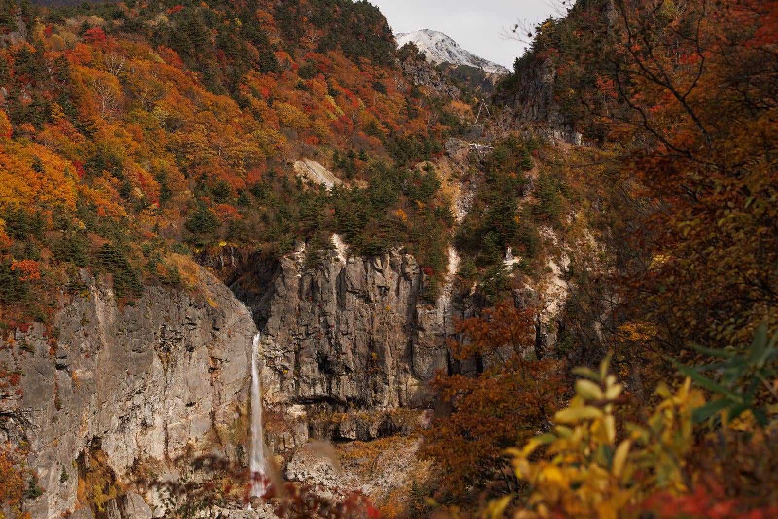 「紅葉に包まれた秋の断壁と白糸の滝」の写真