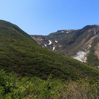 勢至平から眺める新緑と遠景の雪渓の写真