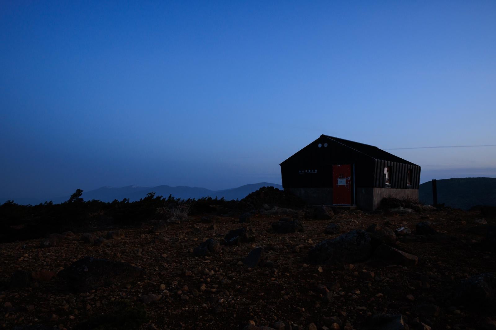 「薄明に浮かび上がる鉄山避難小屋」の写真