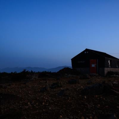 薄明に浮かび上がる鉄山避難小屋の写真