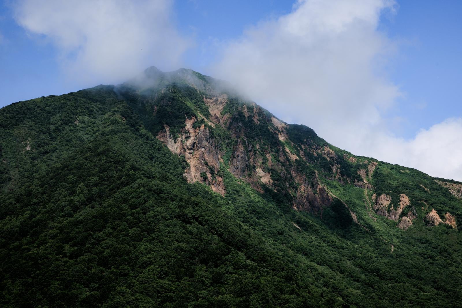 「山肌と雲がかる磐梯山」の写真