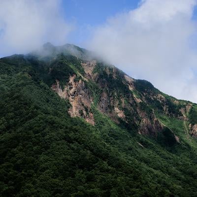 山肌と雲がかる磐梯山の写真