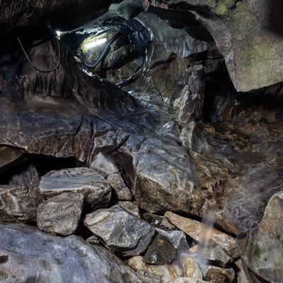 地下水が創る景観、入水鍾乳洞の岩肌と水流にヘッドライトを照らすの写真
