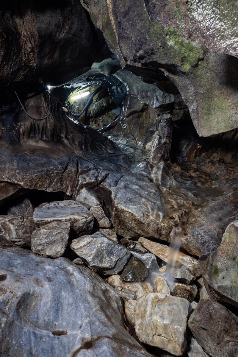 地下水が創る景観、入水鍾乳洞の岩肌と水流にヘッドライトを照らす