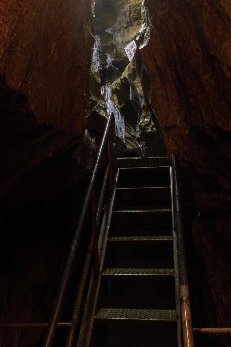 入水鍾乳洞の暗い洞内に設置された金属製の階段と岩肌