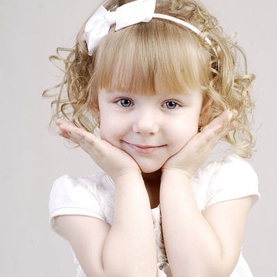 白いドレスを着て可愛さアピールをするブロンドヘアの幼い女の子の写真