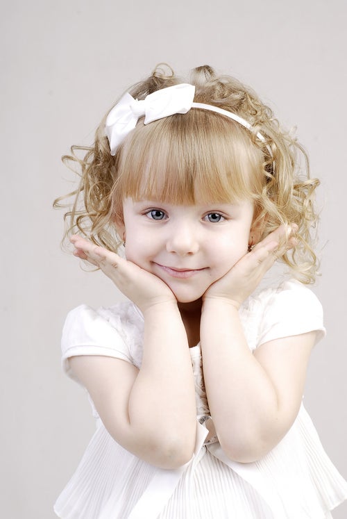 白いドレスを着て可愛さアピールをするブロンドヘアの幼い女の子の写真