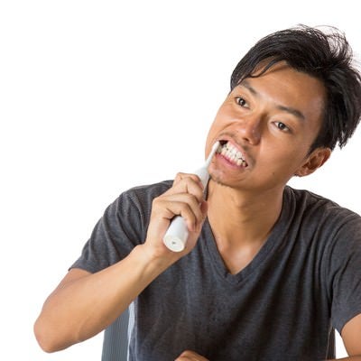 電動歯ブラシで歯を磨く男性の写真