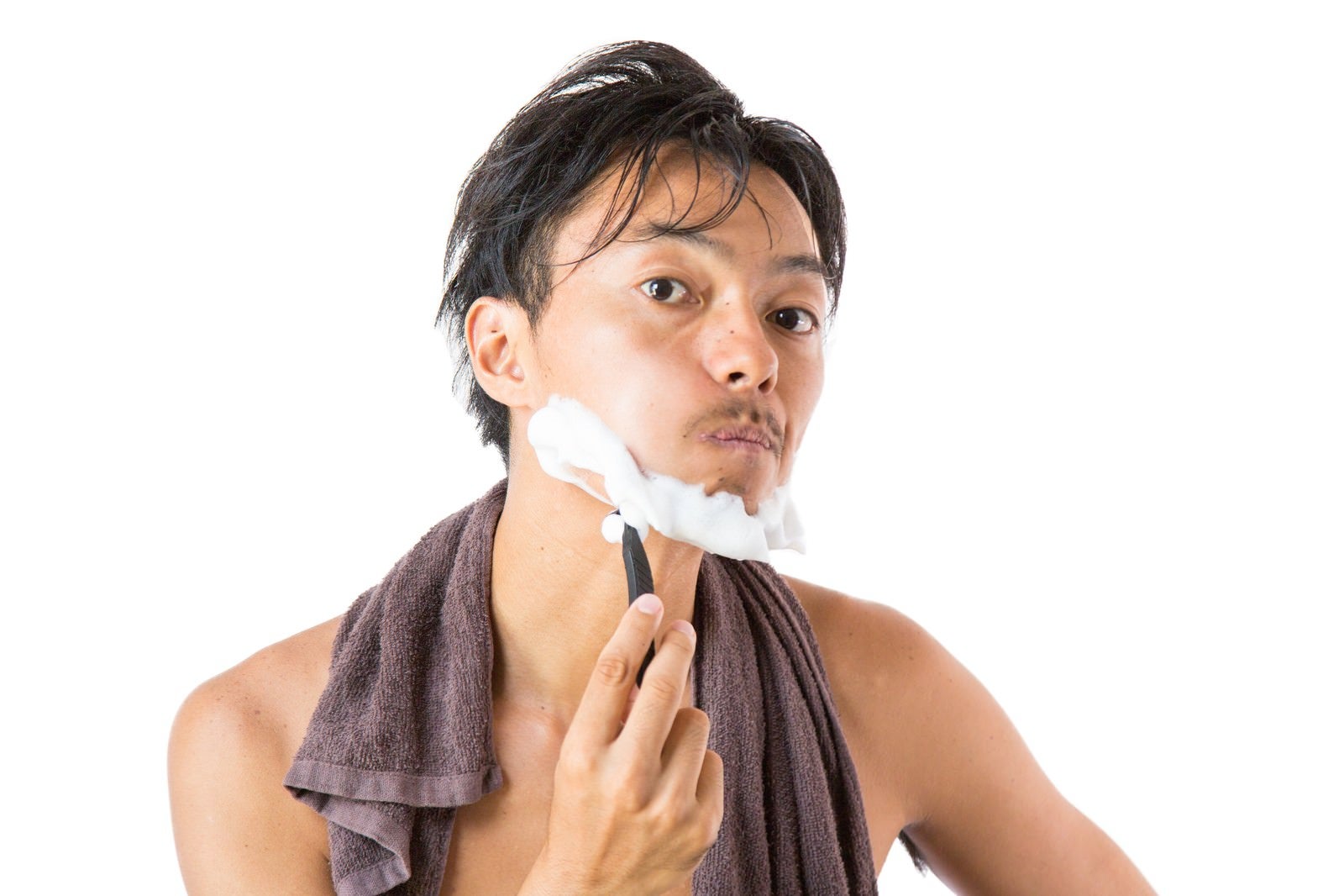 「頬を膨らましながら髭を剃る男性」の写真［モデル：藤沢篤］