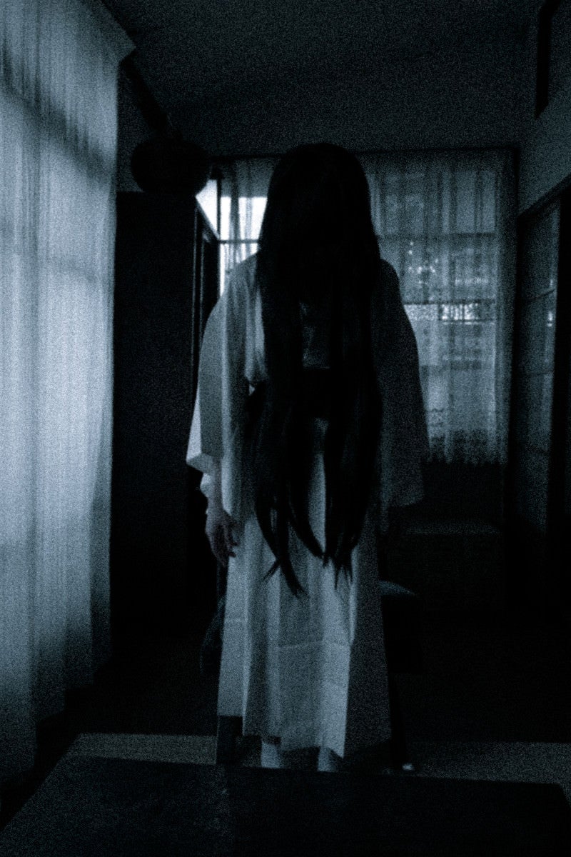 「暗い室内でうつむく長髪の女の霊」の写真［モデル：緋真煉］