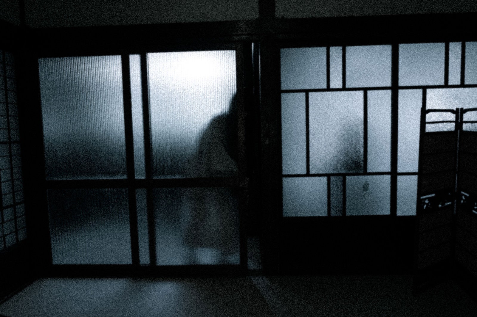 「暗い部屋に入ろうとする人影」の写真［モデル：緋真煉］