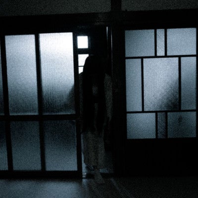 薄暗い部屋に入る黒髪長髪の女性の写真