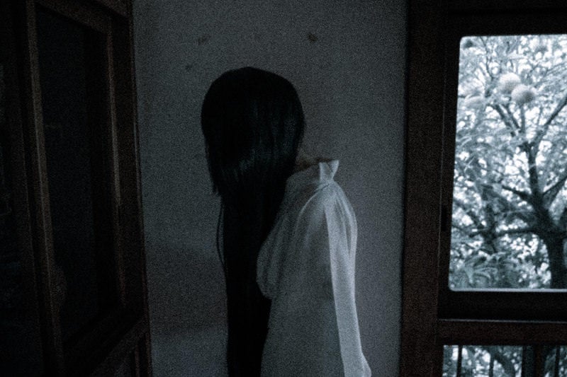 黒髪長髪の女性が部屋の中を徘徊しているの写真