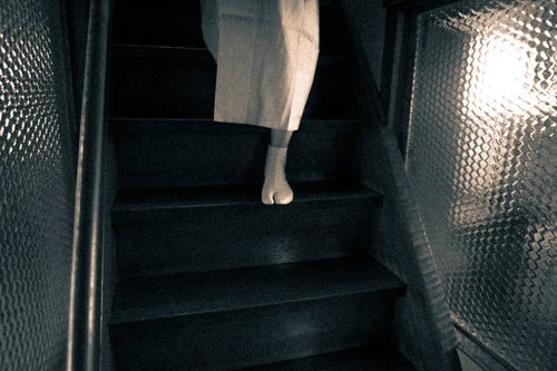 階段を降りてくる女性の片足の写真