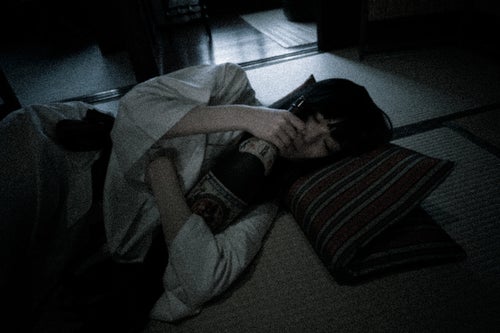 折りたたんだ座布団を枕にして眠る泥酔女子の写真