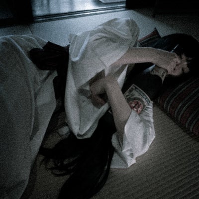 一升瓶を抱えて眠る白装束の女性の写真