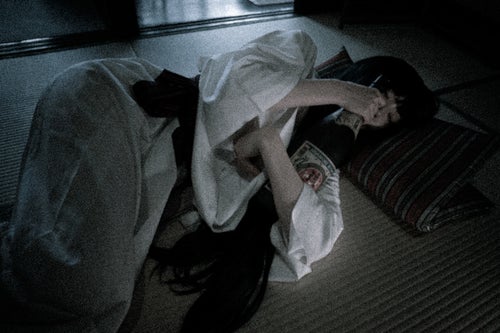 一升瓶を抱えて眠る白装束の女性の写真