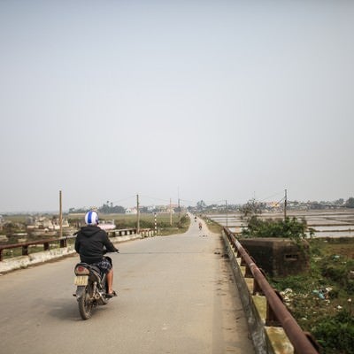 フエ（ベトナム）の田舎道と走行するバイクの写真